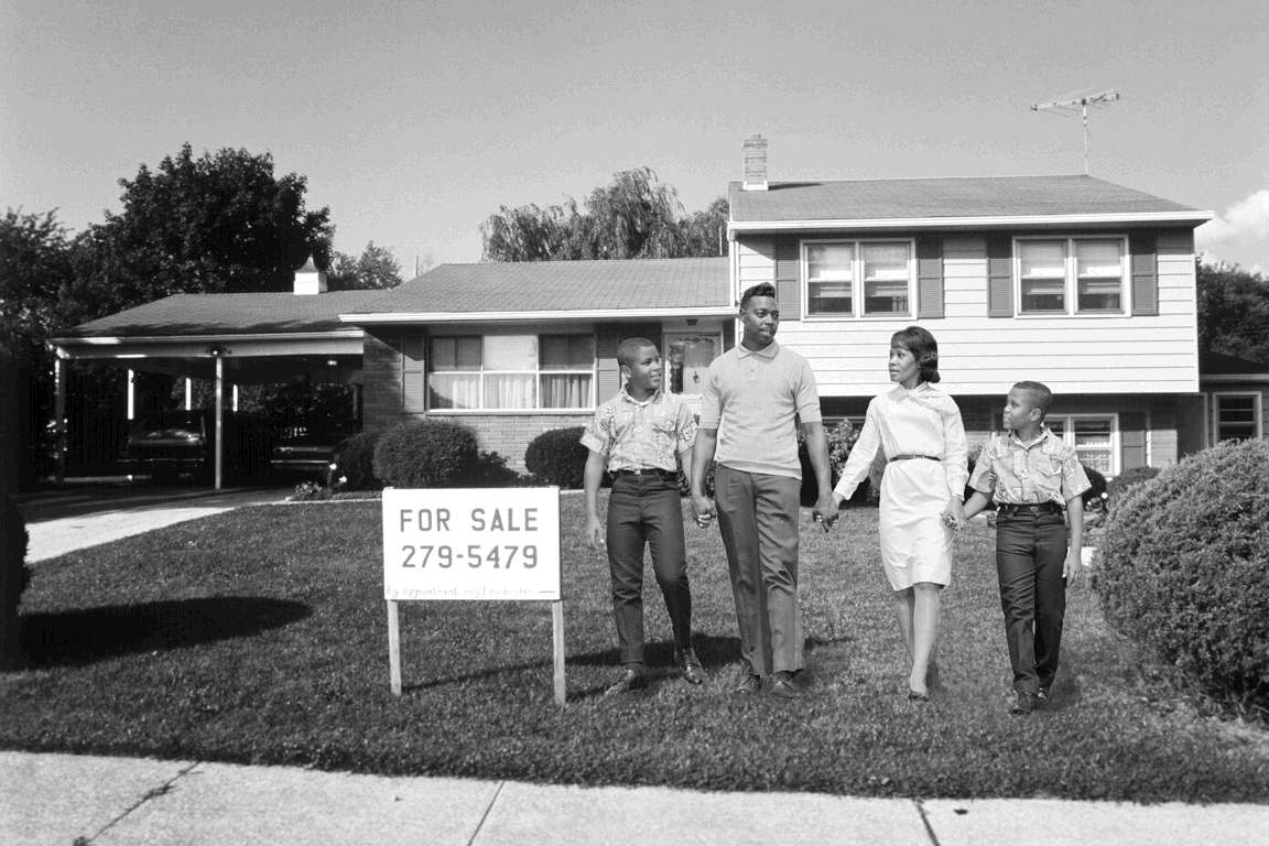 Black family in front of house with 'for sale' sign fading to white family with 'sold' sign