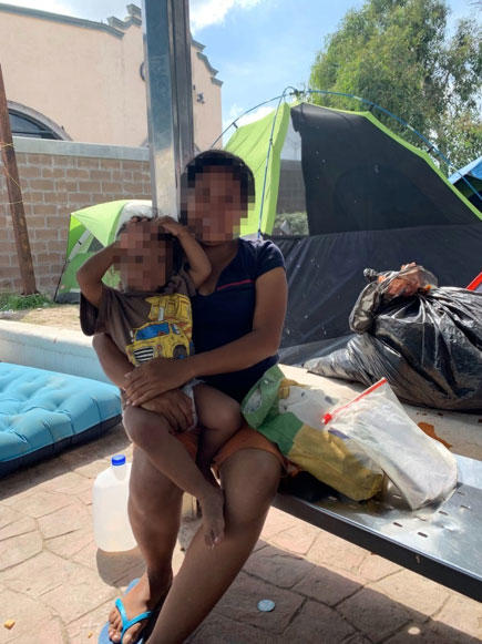 A young pregnant mother holds her toddler in a makeshift migrant encampment created to house asylum seekers sent back to Mexico as a result of the “Remain in Mexico” policy.