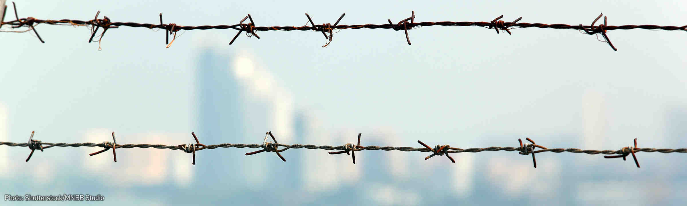 Barbed Wire Fence with City Scape in Background